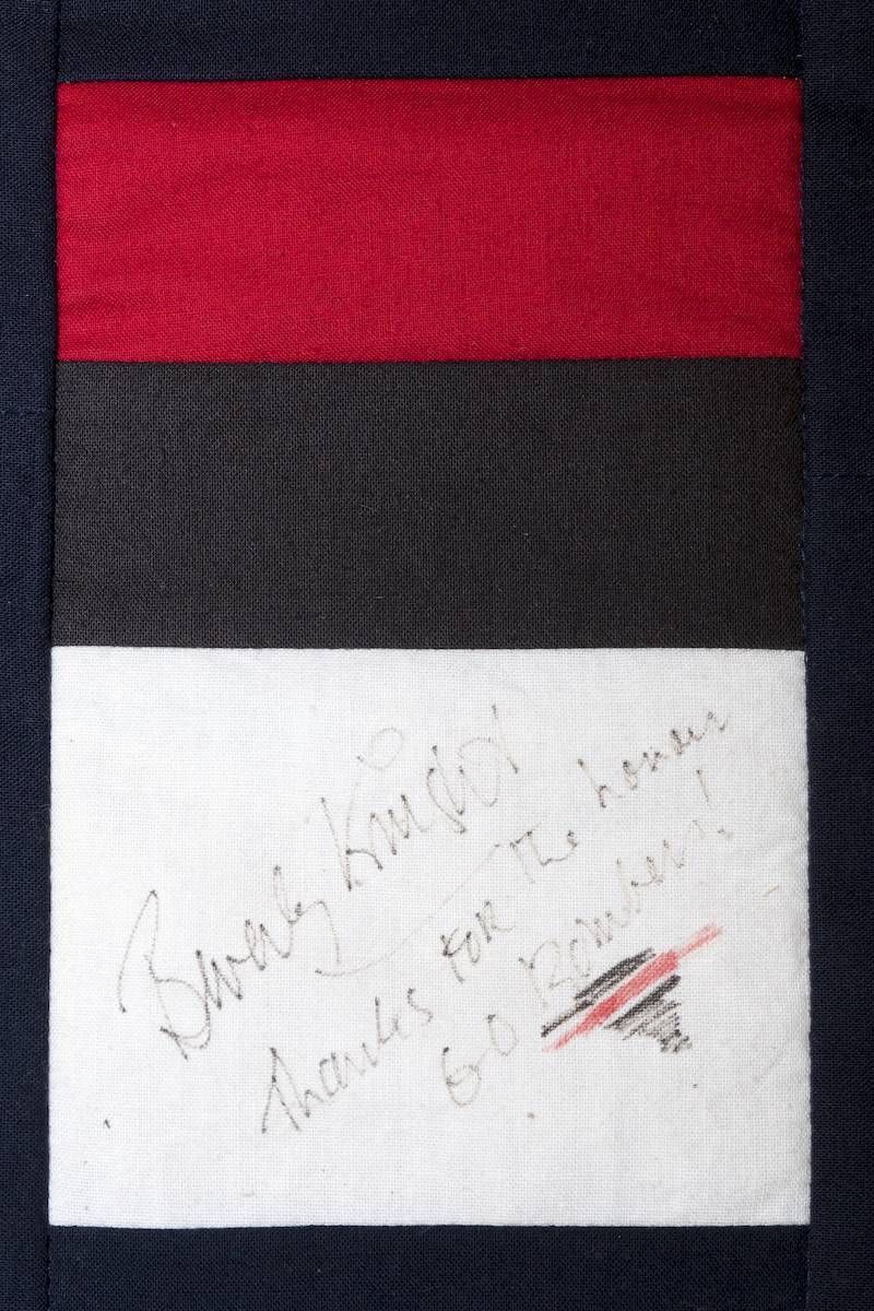 Handwritten note on a red, black, and white tricolor flag-like background