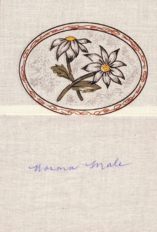 Embroidered daisies in a red oval border with faint blue handwritten text below