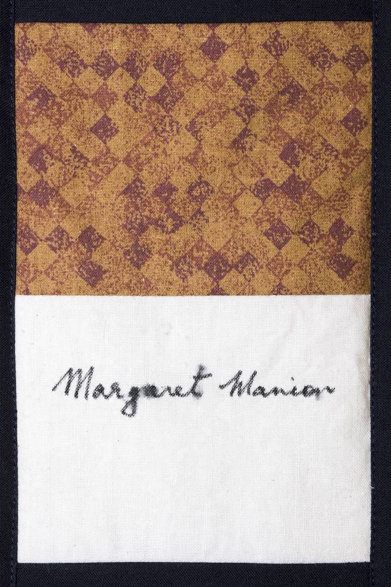 Signed paper with patterned brown top and white bottom, reading “Margaret Harrison”