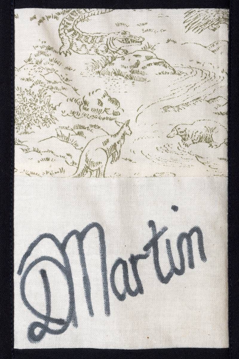 “Martin” handwritten on a white fabric label with a faint floral pattern above