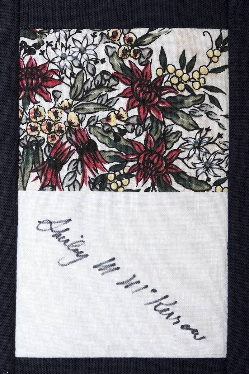Handwritten note on white paper beneath a floral print strip with red and yellow flowers