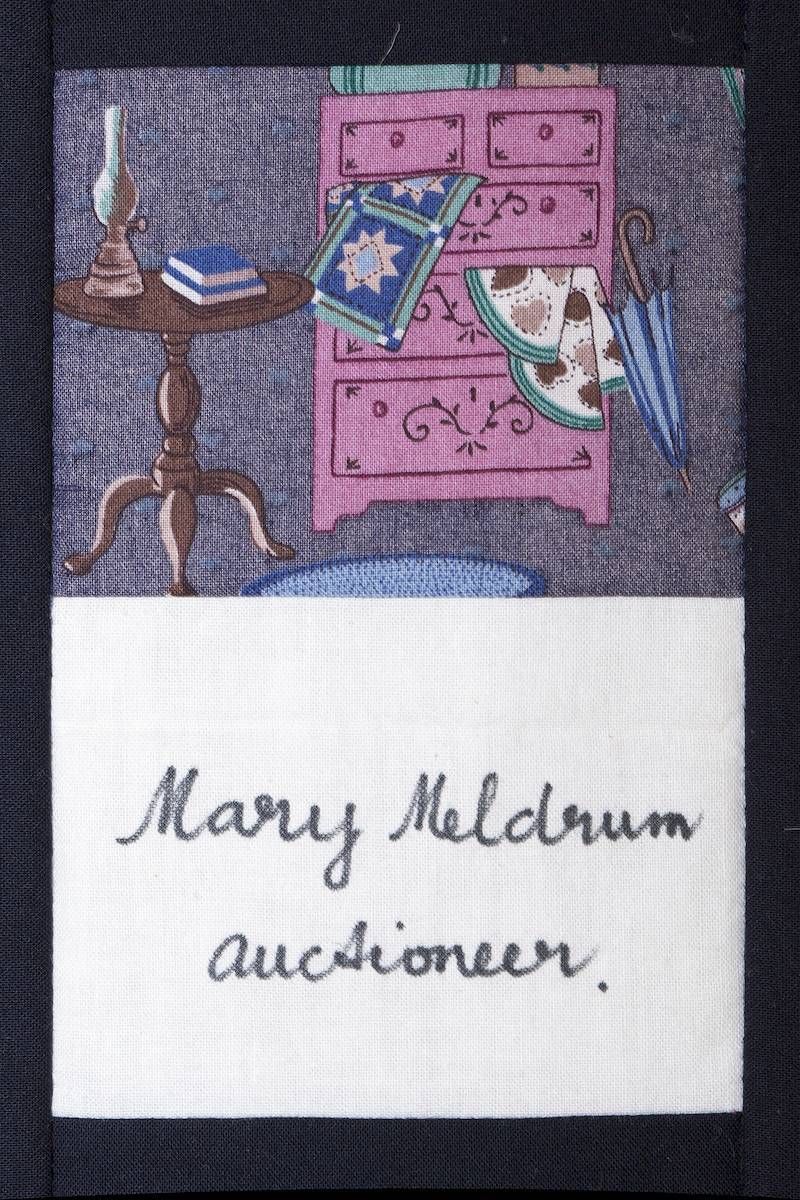 Mary Mcdrum auctioneer label beneath a purple bedroom illustration with a pink dresser and side table