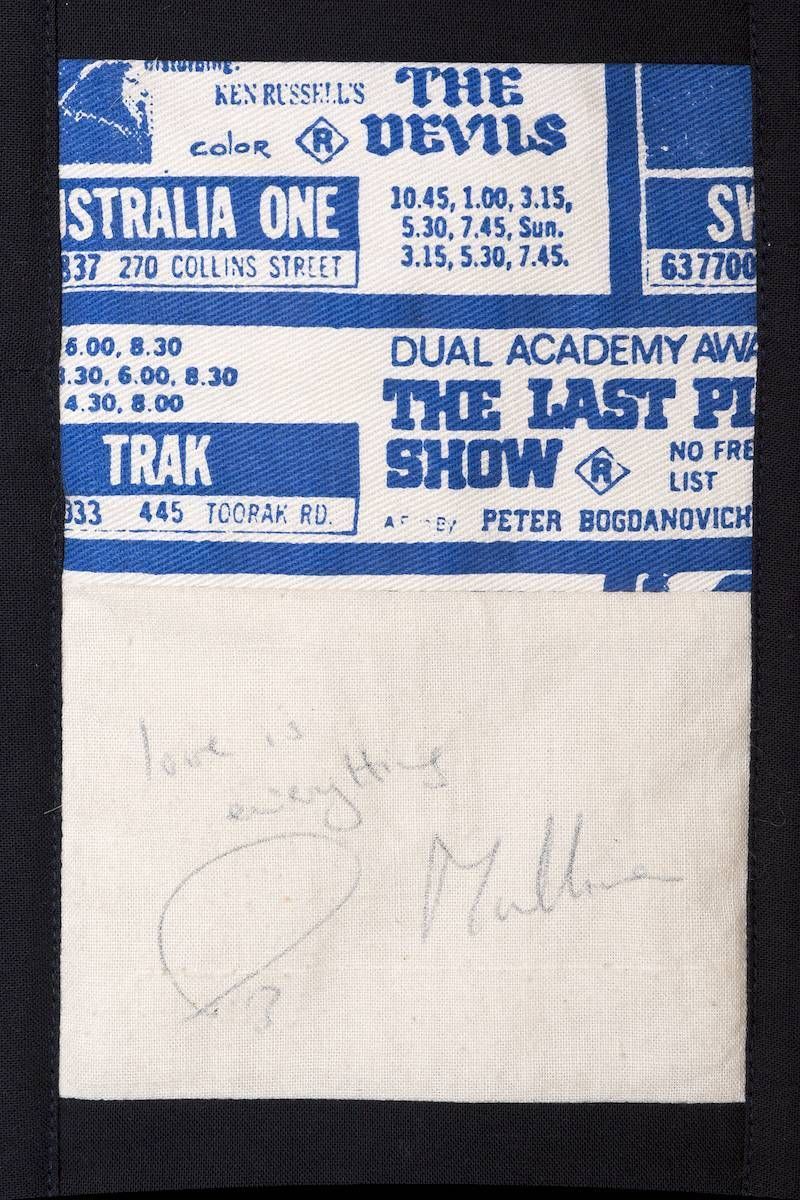 Blue concert tickets above a white note with faint pencil writing on a dark background