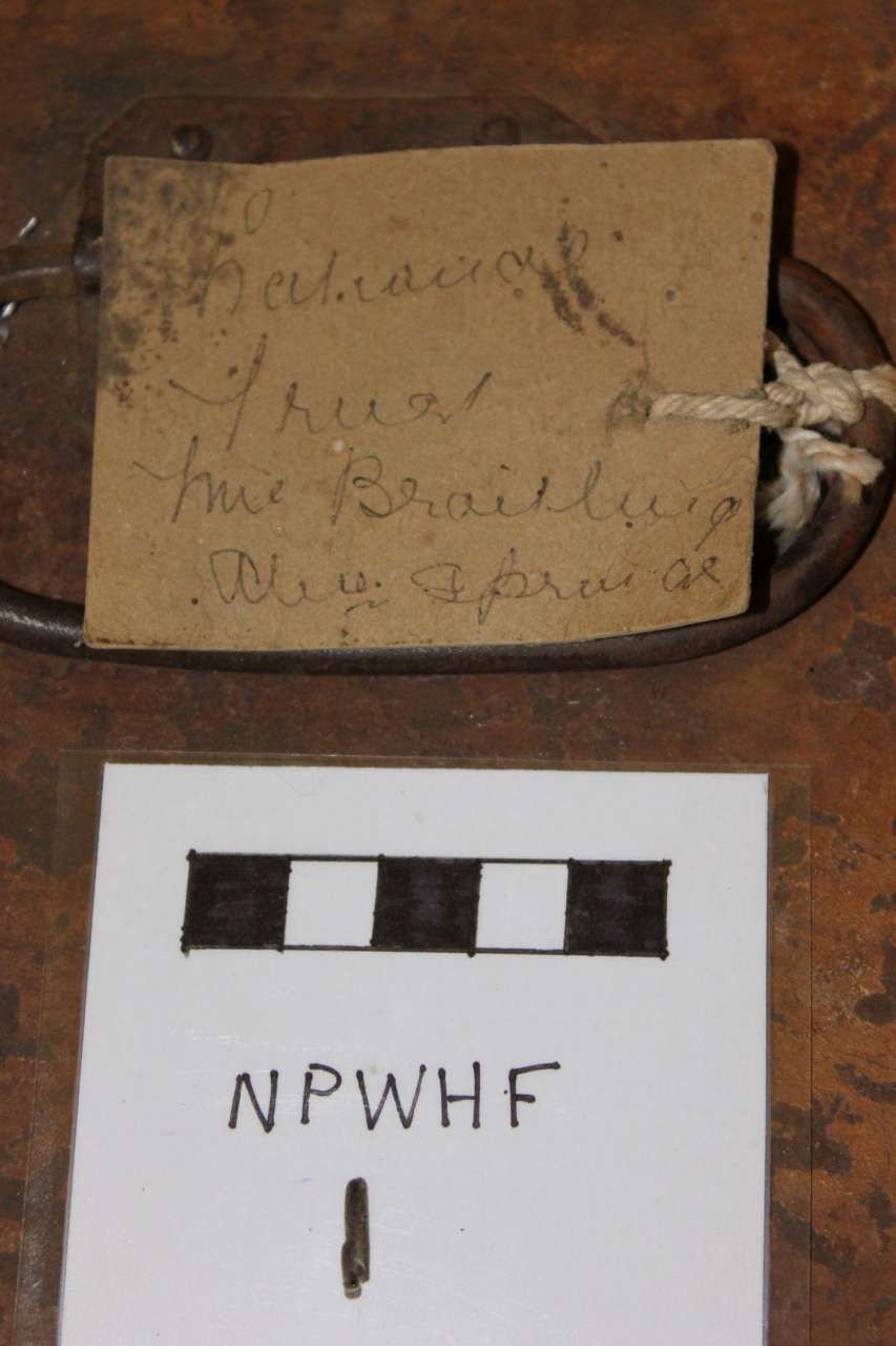 Old handwritten label above a white card marked “NPWHF” with a black-and-white strip