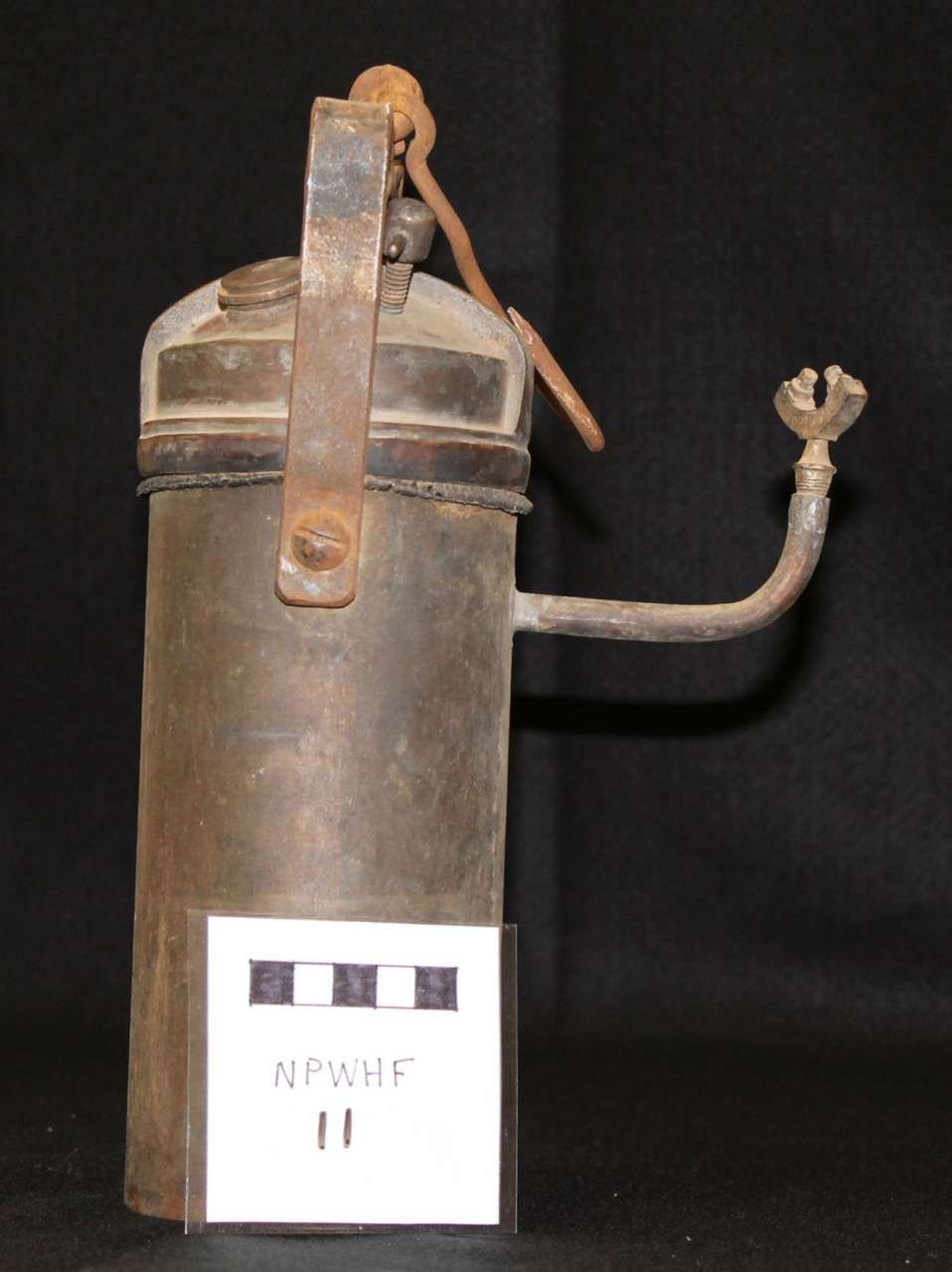 Old metal fire extinguisher with a hose and handle on a black background