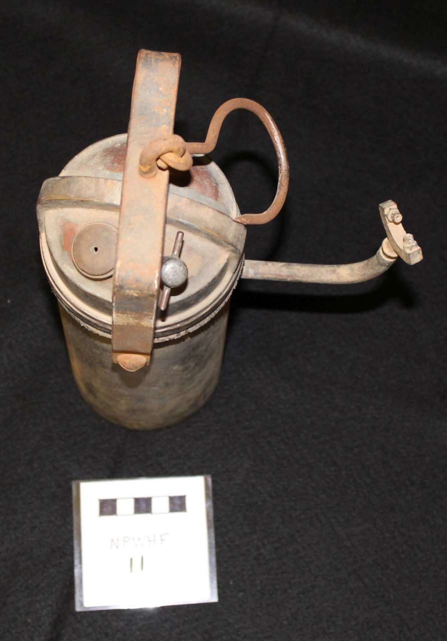 Old metal manual food mill with a crank and wooden handle on a black background