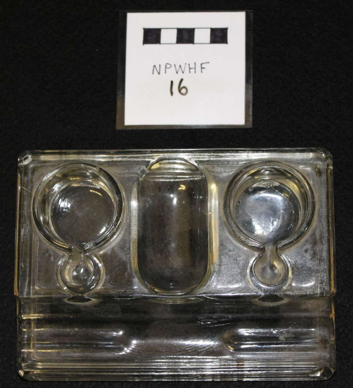 Transparent plastic device with two circular ends and a central chamber, labeled “NPWHF 16” above it