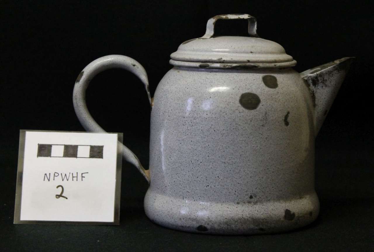 Gray enamel teapot with lid and handle beside a small white label marked “NWNHF 2”