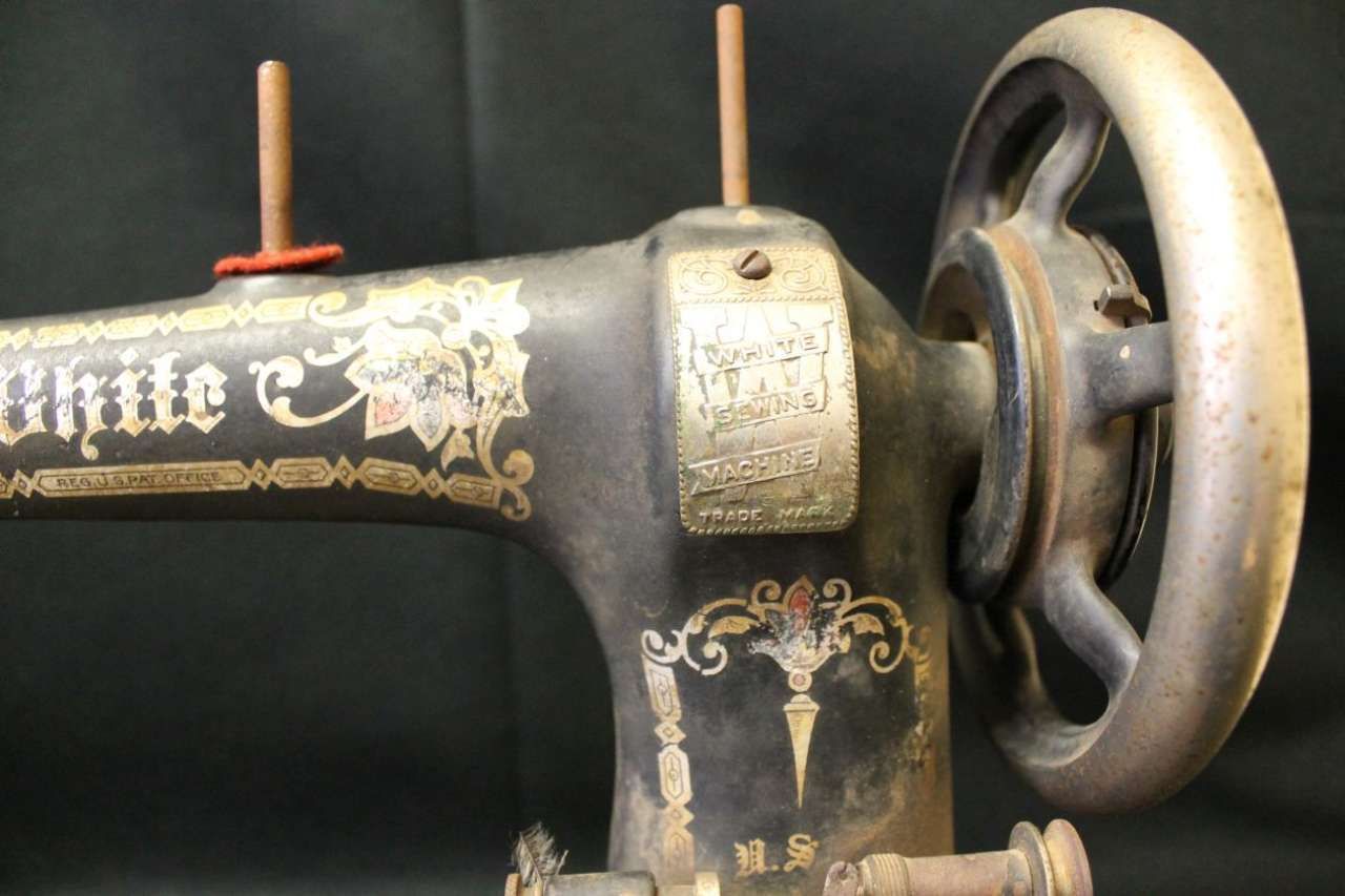 Close-up of a vintage black sewing machine with ornate gold lettering and a handwheel on the right