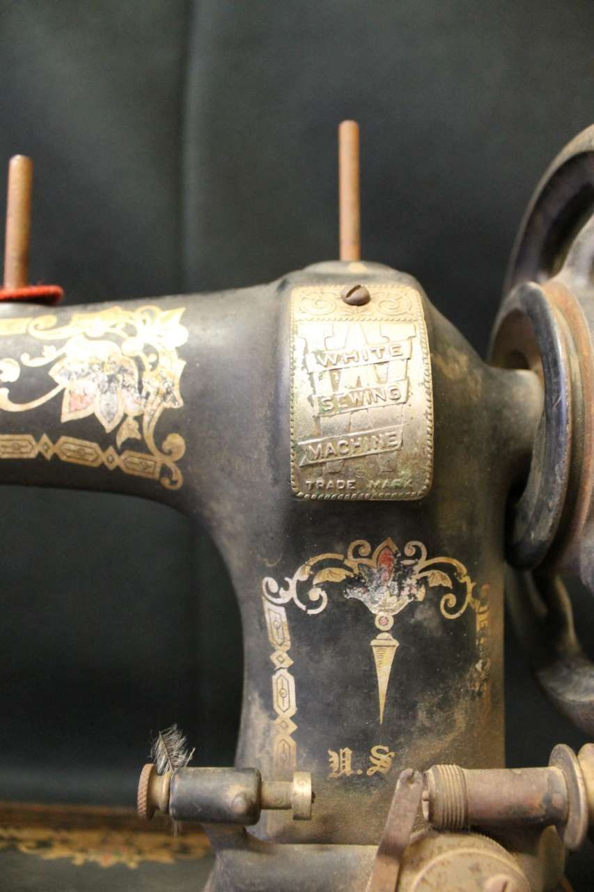 Close-up of a black vintage sewing machine with gold floral decals and metal plate details
