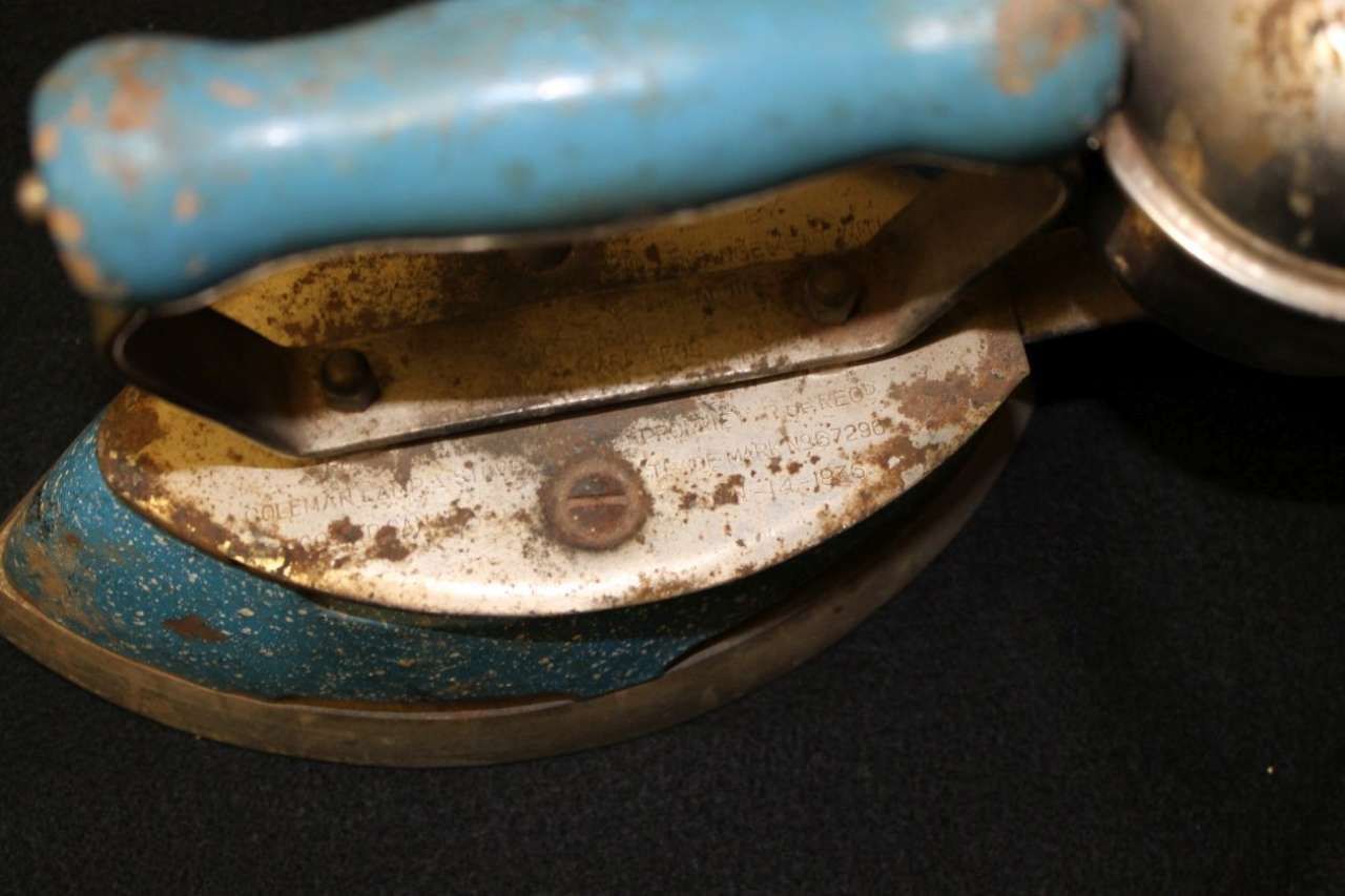 Close-up of a blue and rusted metal tool resting on a dark surface