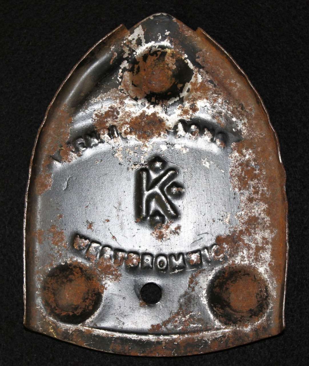 Rusty metal tag with a central logo and the word “LEGION” embossed at the bottom.