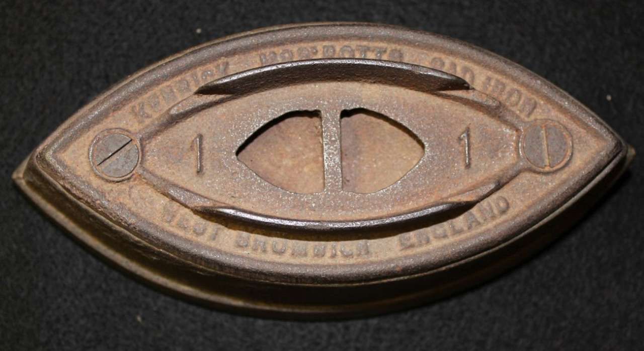 Close-up of a bronze oval metal object with a central eye-shaped design on a dark background