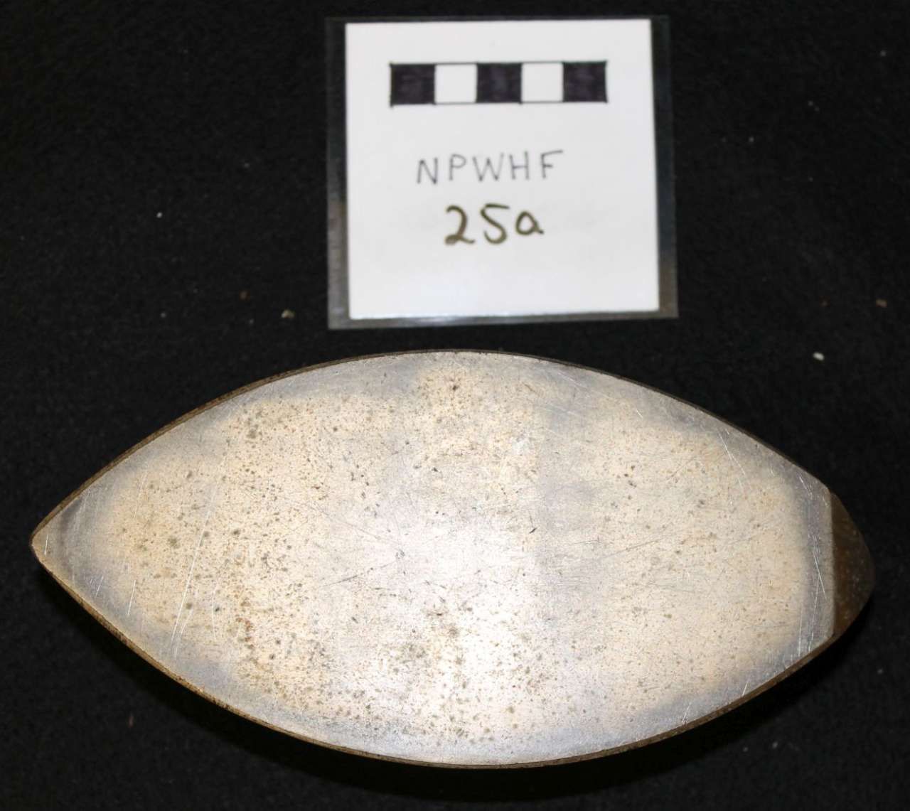 Silver oval object below a labeled white square card on a black background