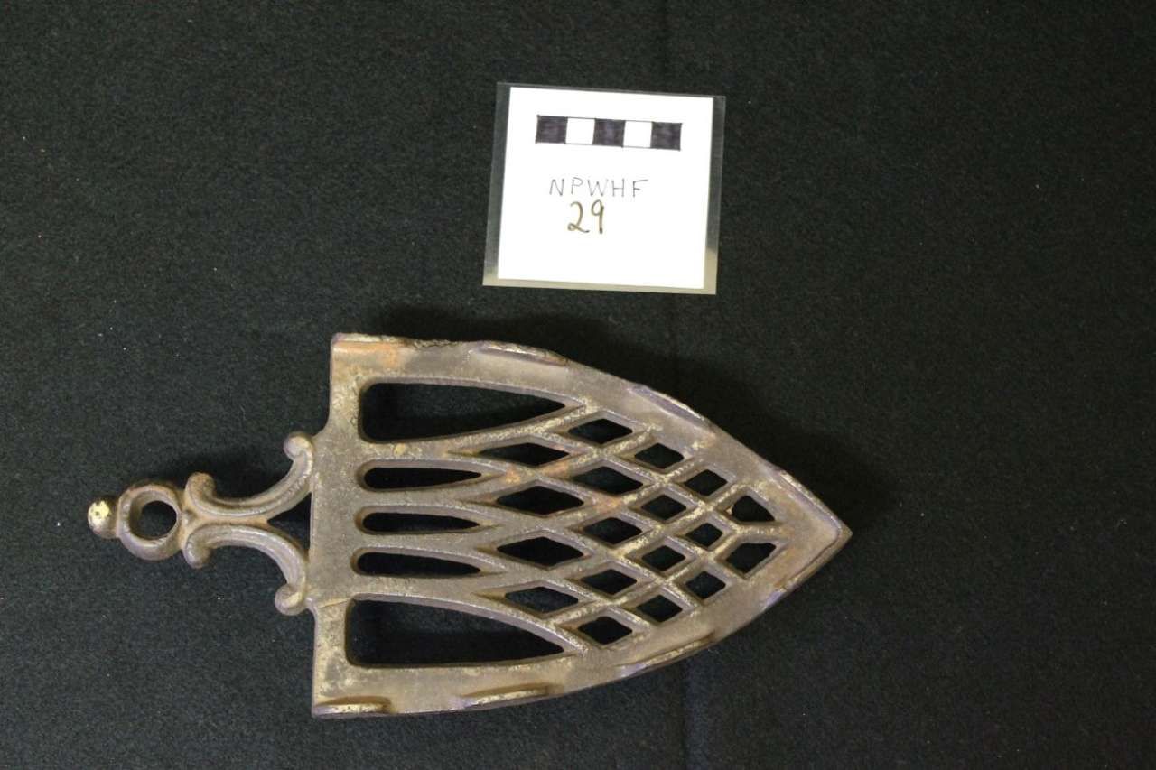 Metal fish-shaped pendant with lattice cutouts on a black background, labeled with a small white tag