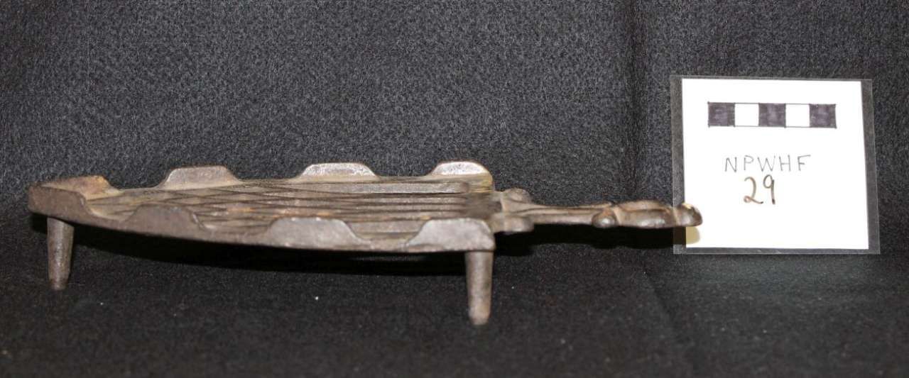 Ancient flat carved artifact on a dark surface beside a small label card.