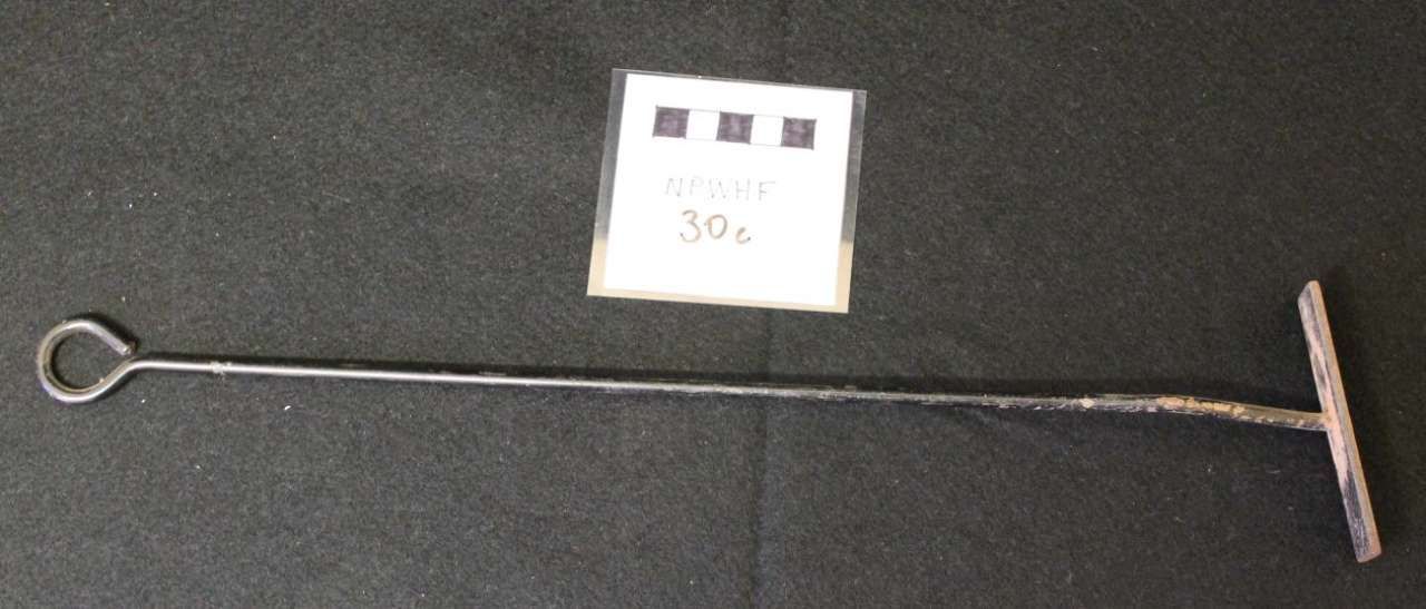 Long metal rod with a looped end and T-handle, with a small labeled card on a dark surface.