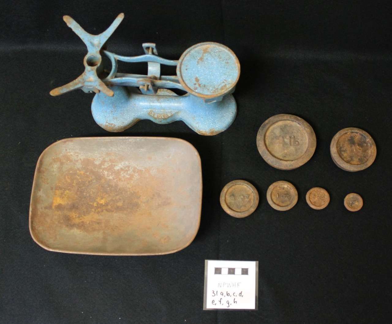 Rusty antique metal objects and assorted old coins arranged on a black background.