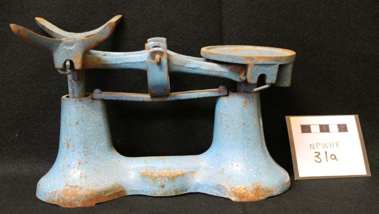 Antique blue metal weighing scale with tray and circular platform on a dark background