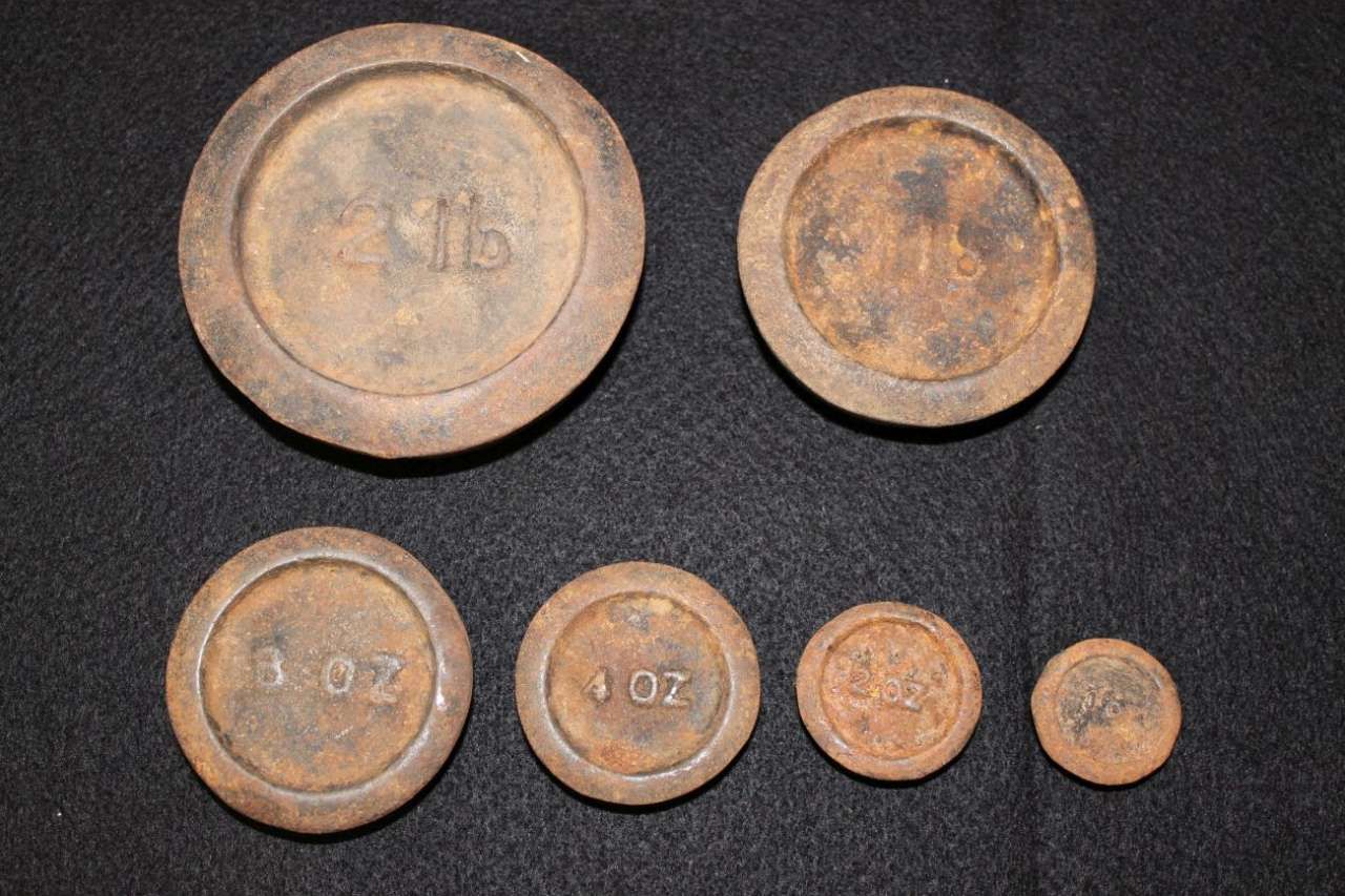 Five rusty coins arranged on a dark surface, largest on the left and smallest on the right.