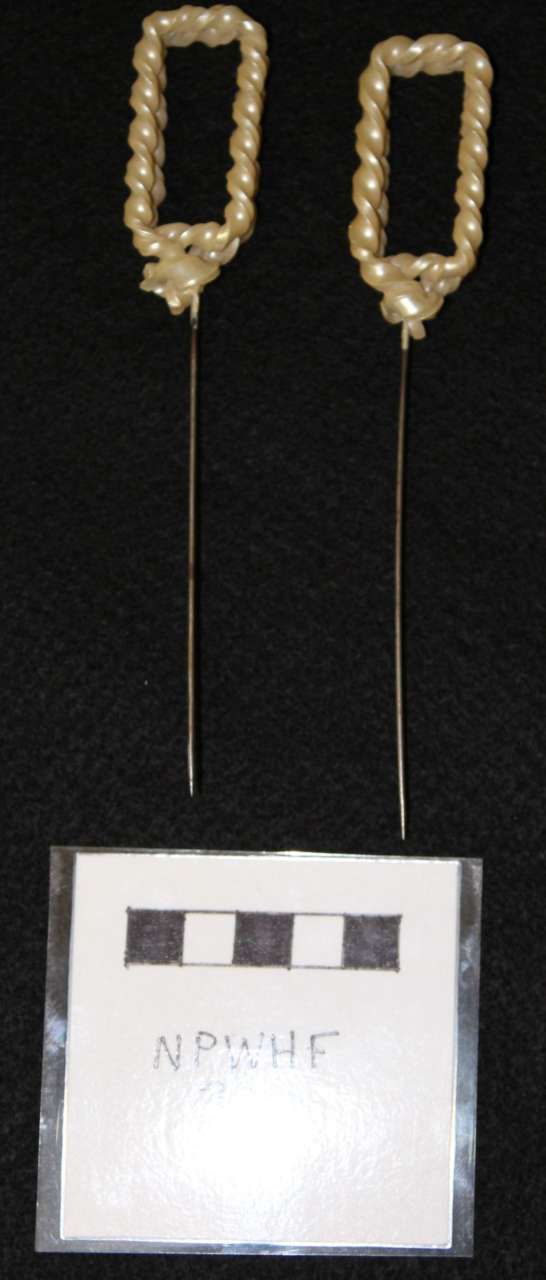 Two gold beaded drop earrings displayed above a small white label on a black background