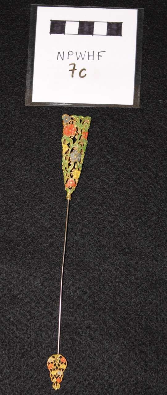 Small floral pendant with a thin chain beneath a labeled white card on a black background