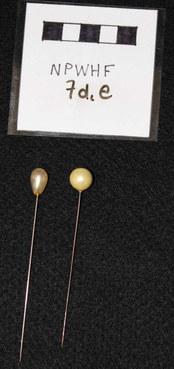Two gold teardrop beads with wires beside a label reading “NPWHF 7d.e”