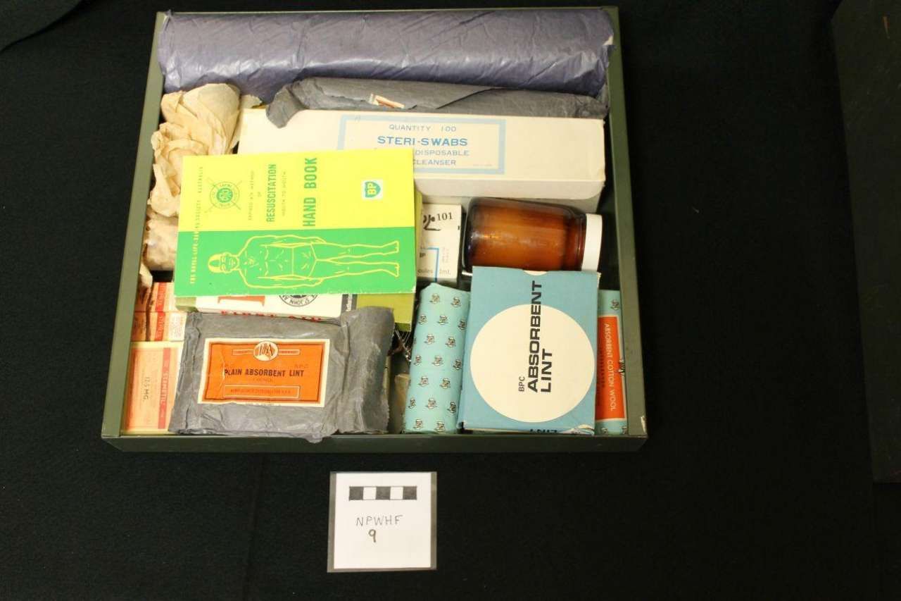 Open box of assorted small packages and items in a dark green container.