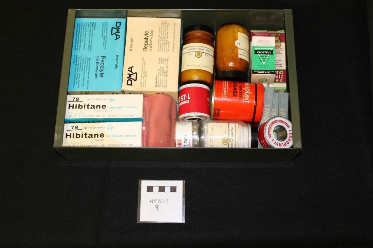 Open medicine drawer with assorted pill bottles, boxes, and a small card below.