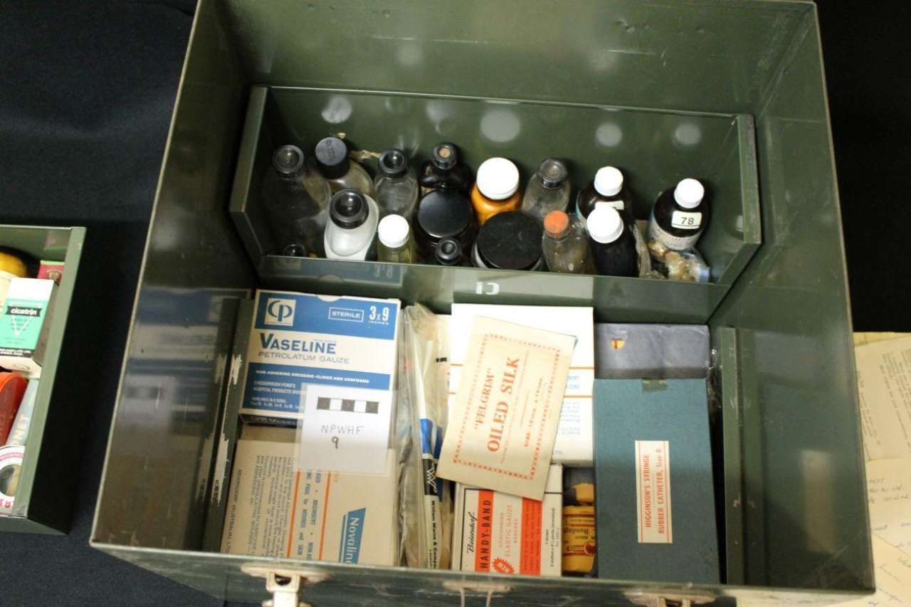 Open box with assorted medicine bottles and packages arranged in compartments