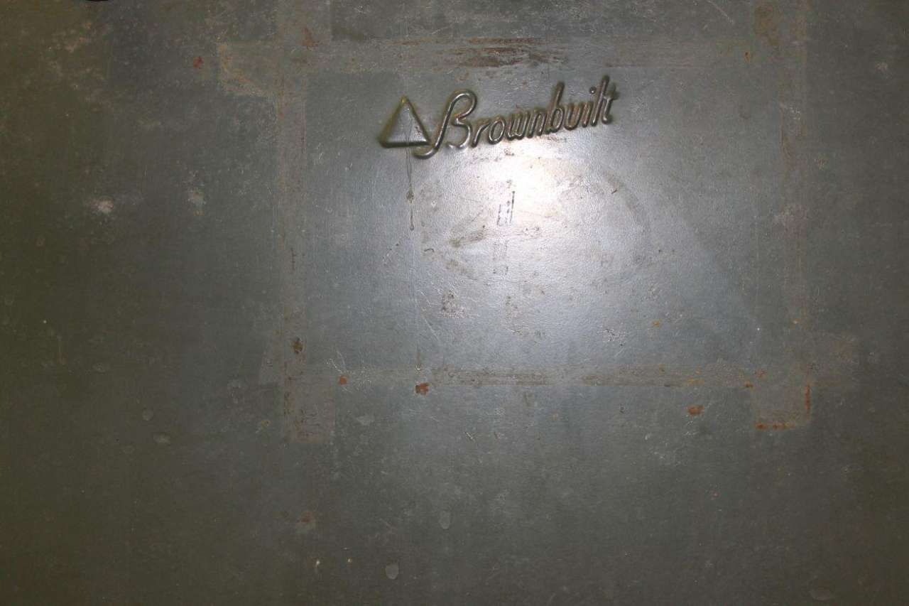 Dim gray metal surface with a small embossed logo near the top and a bright glare in the center