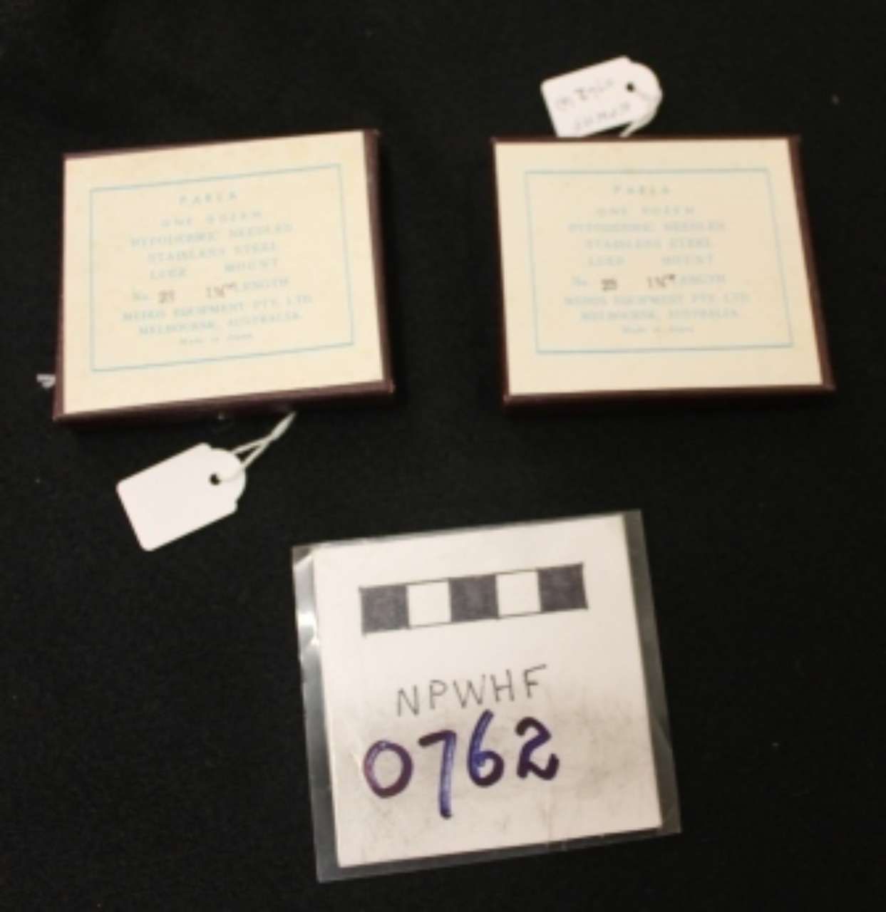 Three framed certificates with tags and a labeled archival box on a dark surface