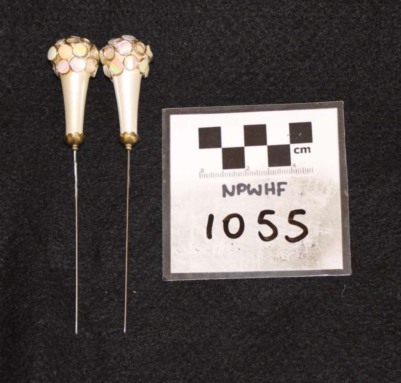 Two small cream beaded drop earrings beside a black-and-white measurement label marked 1055.