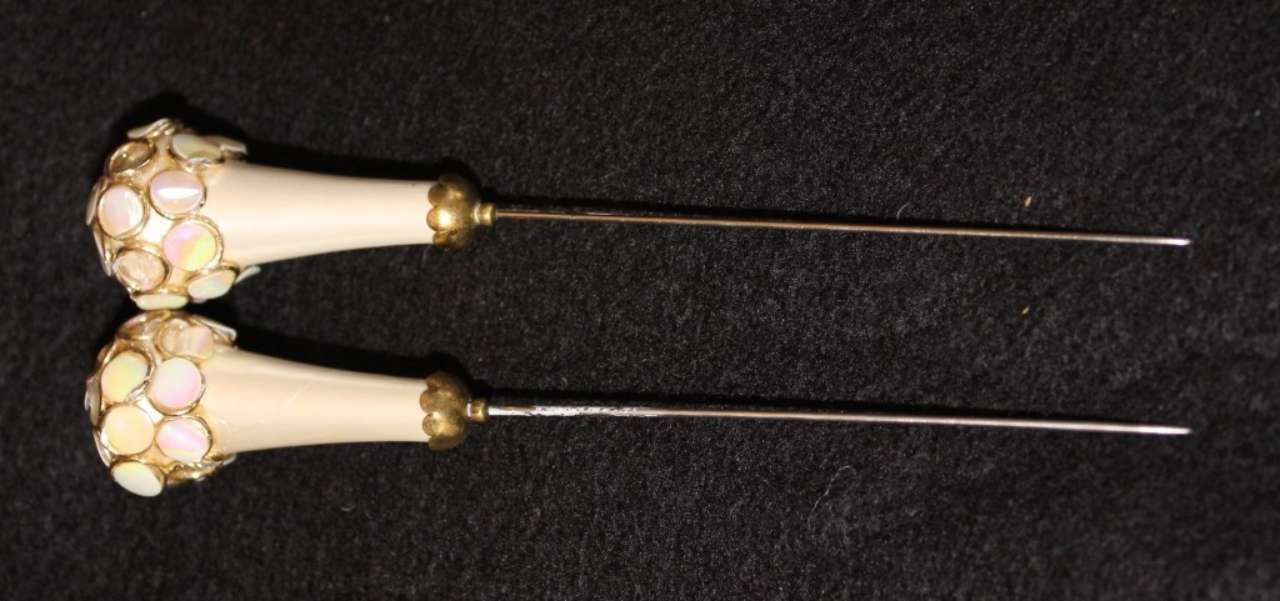 Two ornate ivory hair sticks with gold accents on a black background