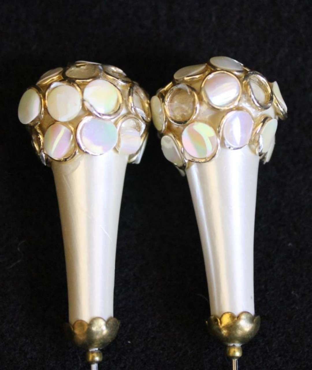 Pair of ornate white-and-gold decorative jewelry pieces on a black background