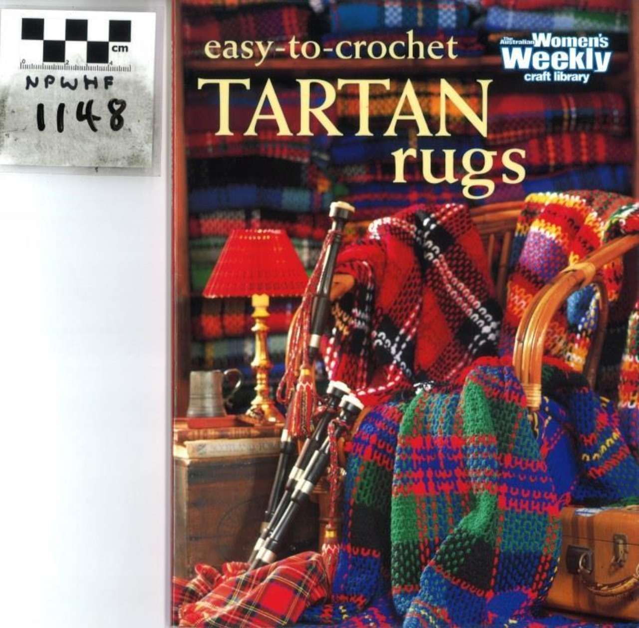 Cover of a crochet magazine featuring colorful tartan rugs and home decor, with a black-and-white label in the corner