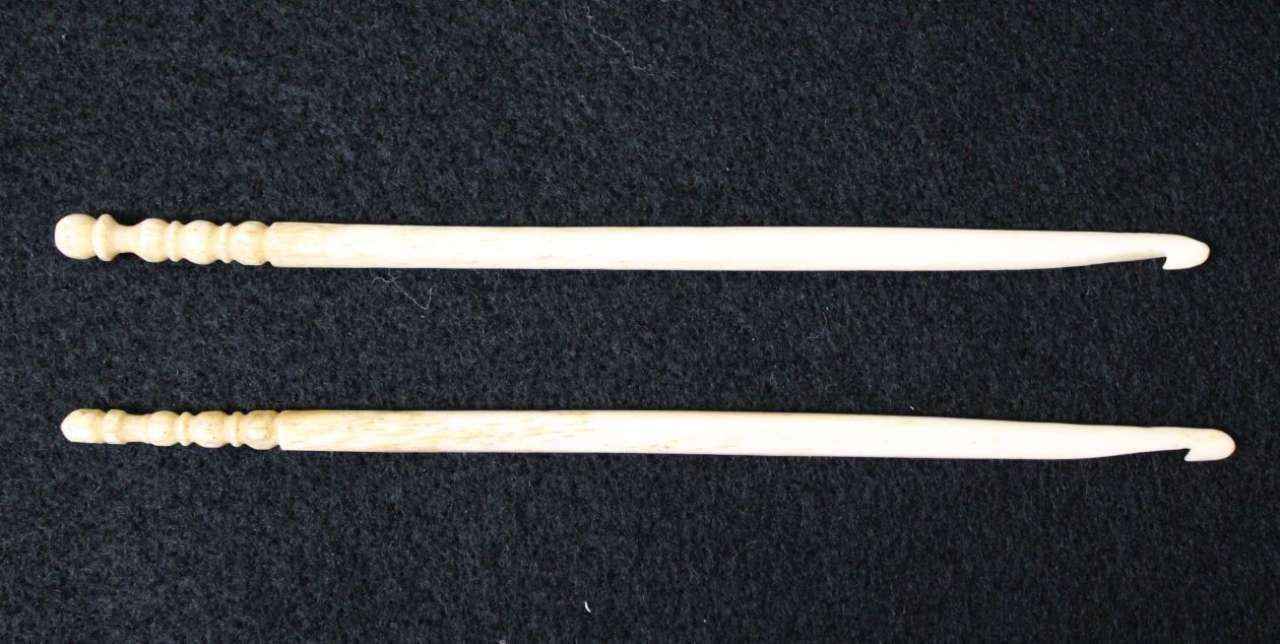 Two carved white bone hairpins on a black background