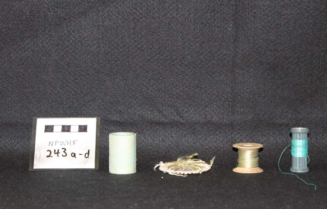 Small labeled display of five objects on a dark background, including a white tag and three small containers.