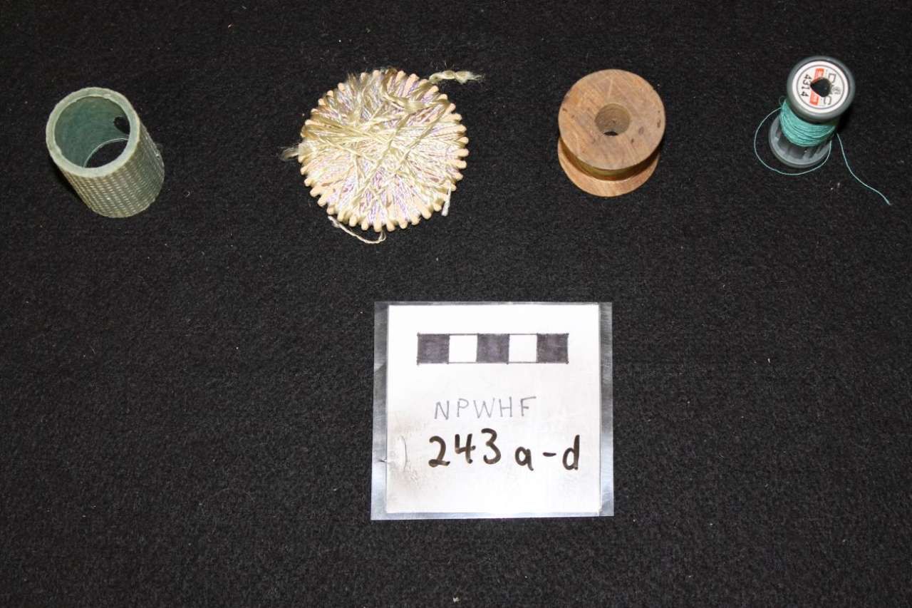 Four small mechanical parts laid out on a black background with a labeled evidence card below.