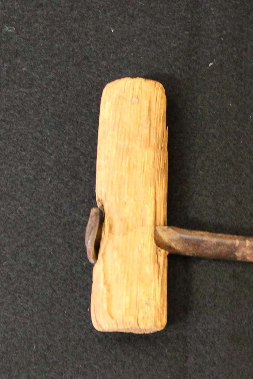Small wooden block with a metal rod inserted through it on a black background