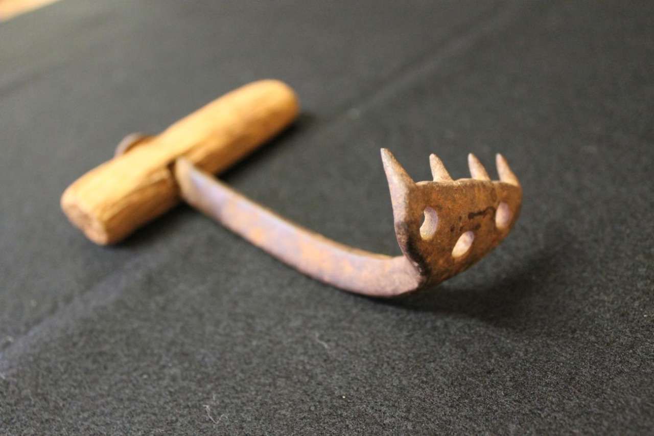 Rusty metal rake head with wooden handle on a dark fabric surface