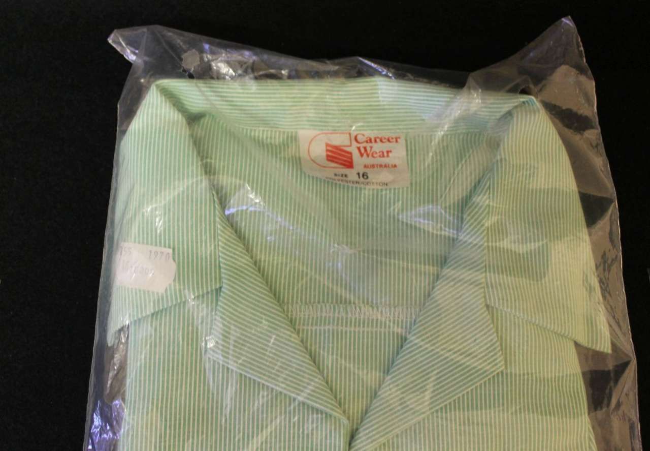 Green striped garment sealed in a clear plastic bag with a red label.