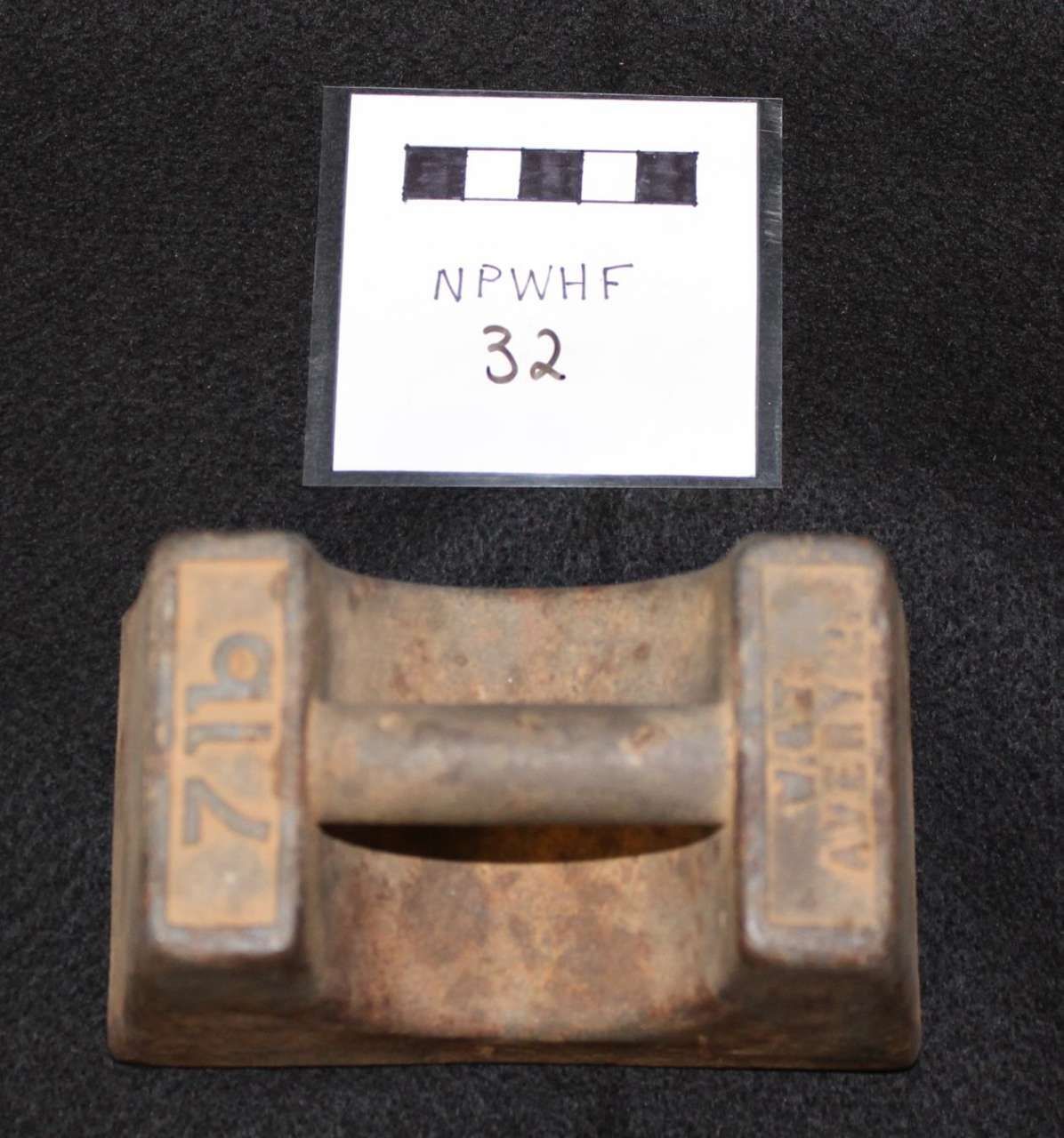 Rusty metal object with label card on a dark background