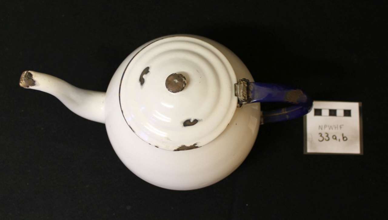 White teapot with lid on a black background, labeled with a small tag