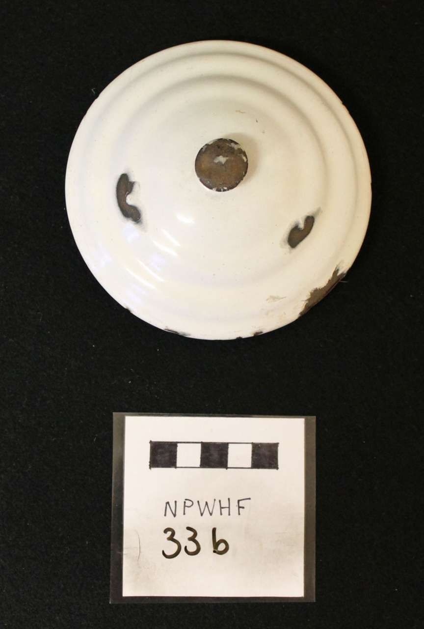 White circular metal part with three cutouts above a labeled scale card marked “NPWHF 336”