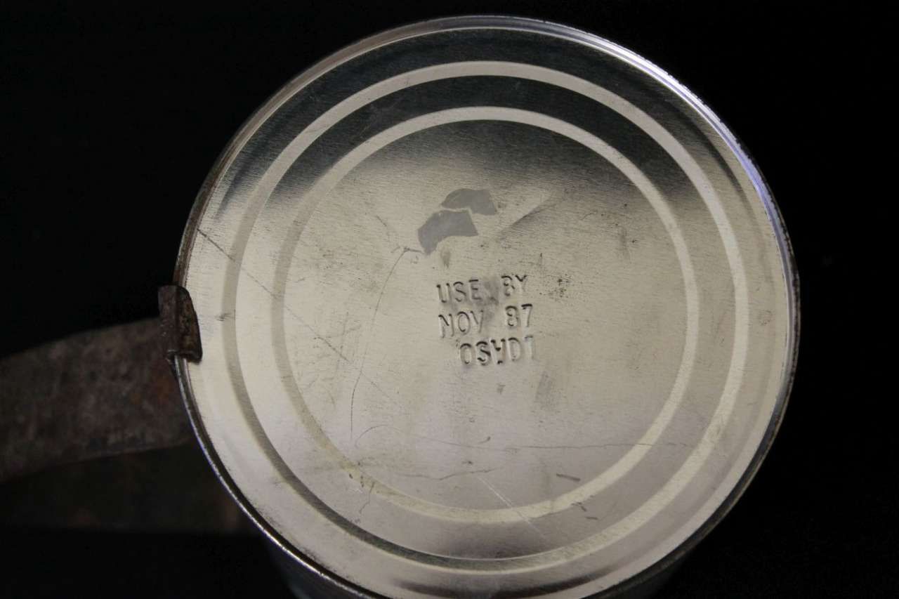 Close-up of a metal saucepan base with stamped markings on a dark background