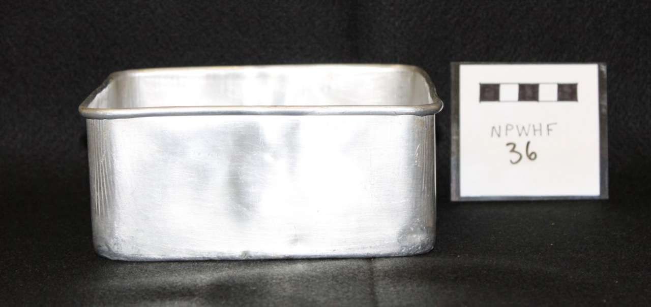 Silver metal rectangular container beside a small labeled card on a black background