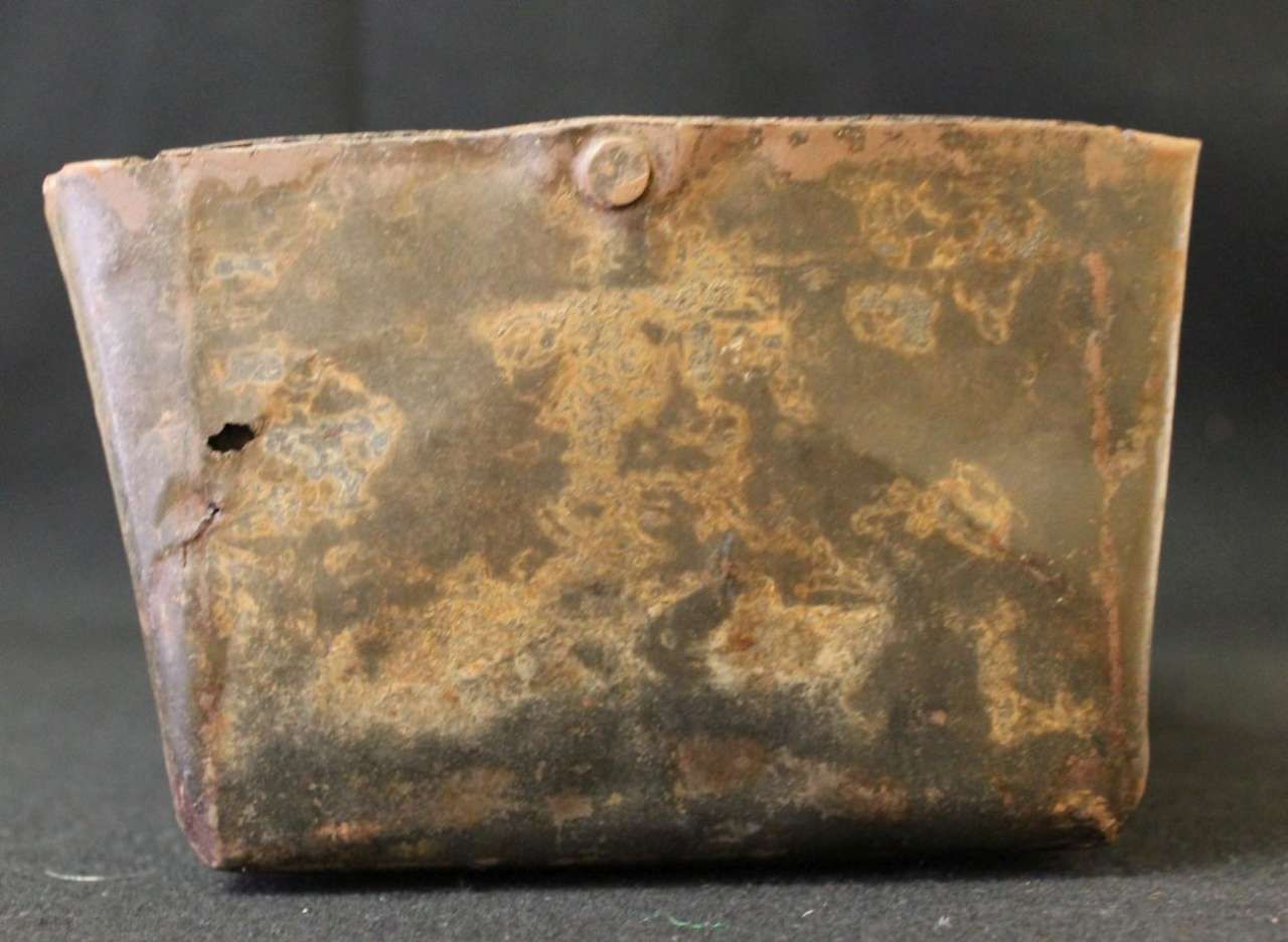 Rusty old metal canteen or tin container with a worn, dented surface and small hole