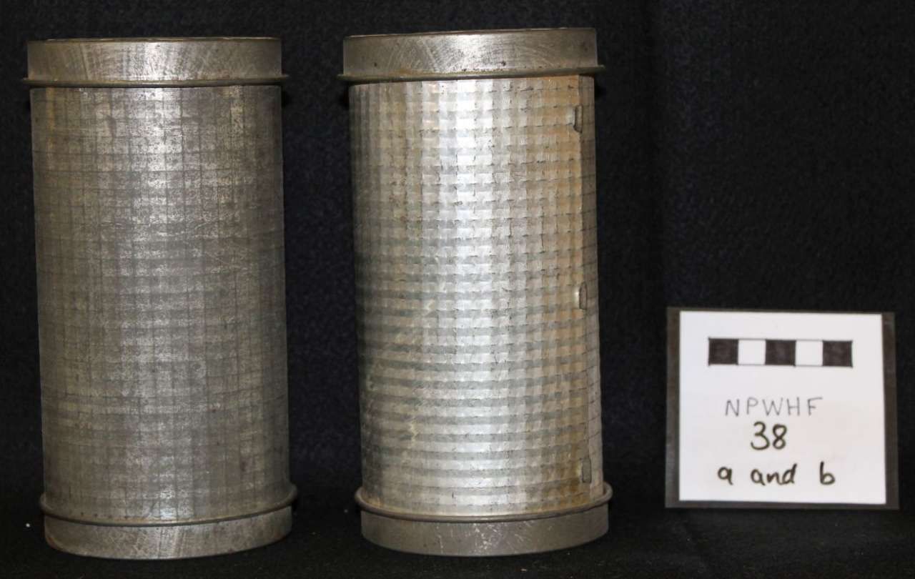 Two silver cylindrical mesh containers beside a small white label card on a black background