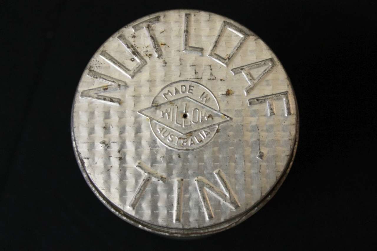 Close-up of a silver metal button with raised lettering and a small central emblem.